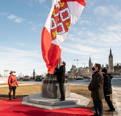 Administrator Richard Wagner raising a large flag on a flag pole.