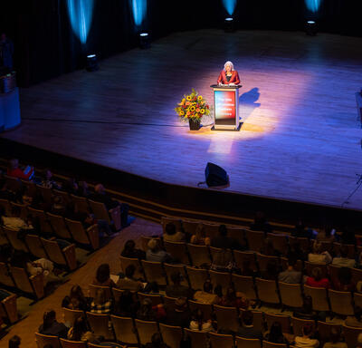 View from the balcony of the Jack Singer Concert Hall in Calgary. The Governor General is standing at a podium on the stage.