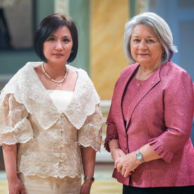 Governor General Simon is standing next to Her Excellency Maria Andrelita Sacramento Austria.